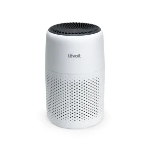 Levoit Core Mini Air Purifier in white with a black top, featuring a perforated design, set against a plain background.