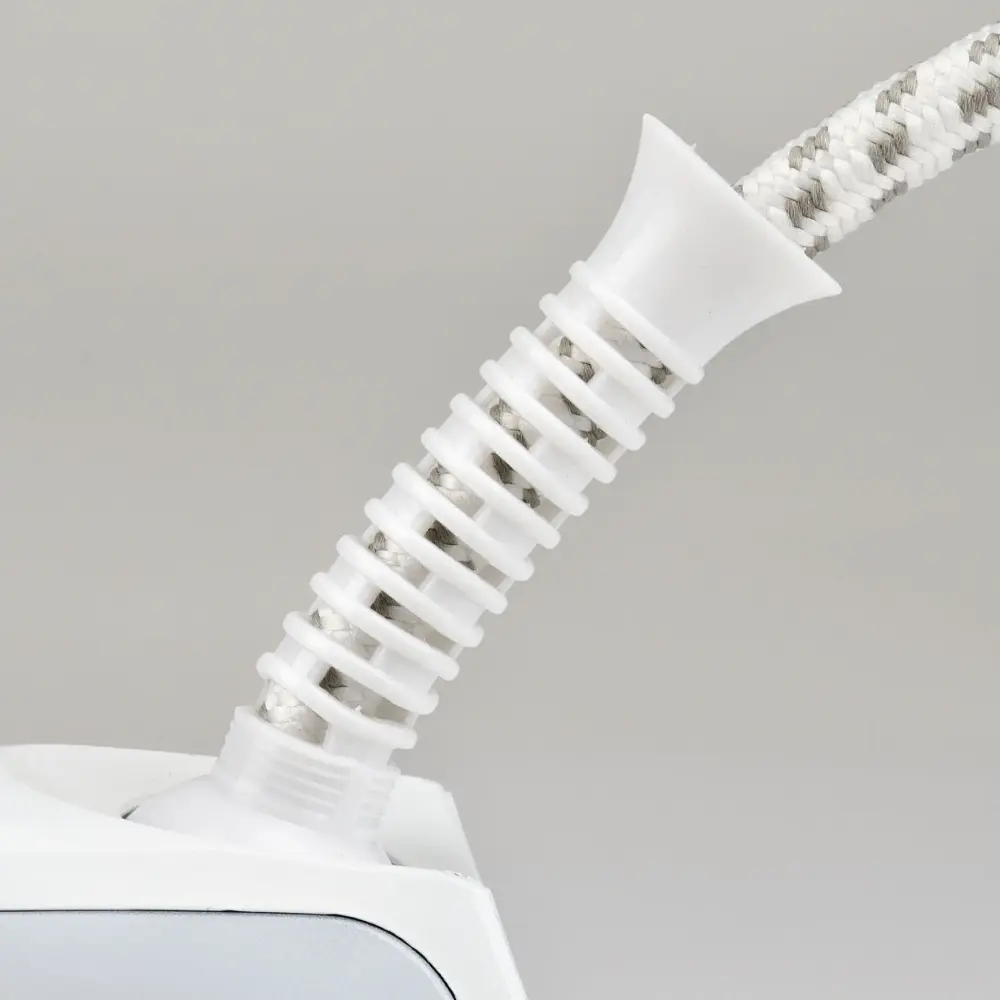 Close-up of the white G3 Ferrari 900W Seicento G40013 dry iron’s braided power cord and flexible strain relief against a gray